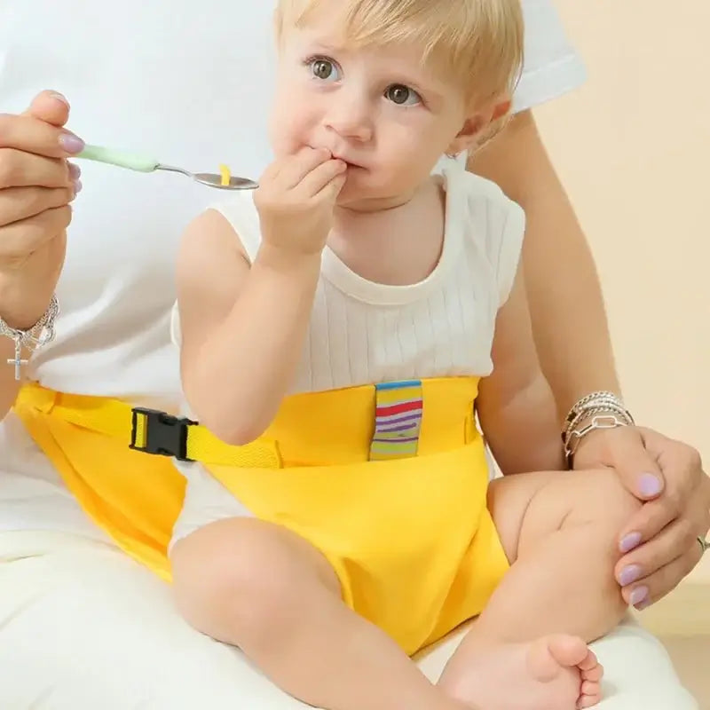 Child in a yellow safety harness enjoying a meal, demonstrating the PANGDUBE Portable Baby Meal Strap in use.